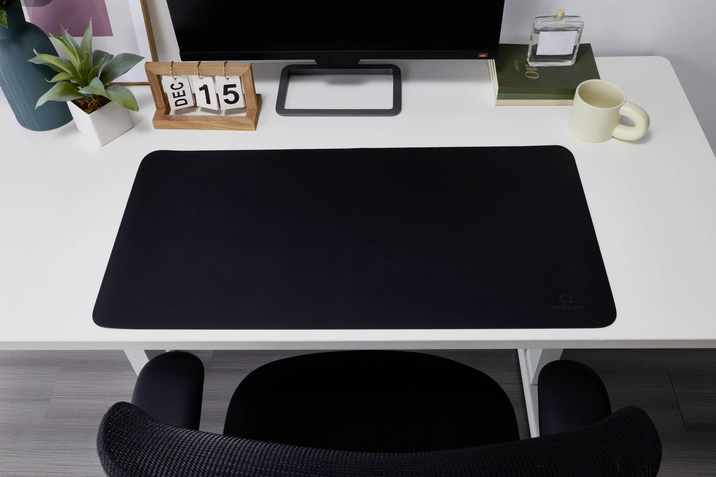 Schreibtisch mit schwarzem Mauspad, Monitor, Pflanze und einem Kalender, der auf '15. Dezember' steht.