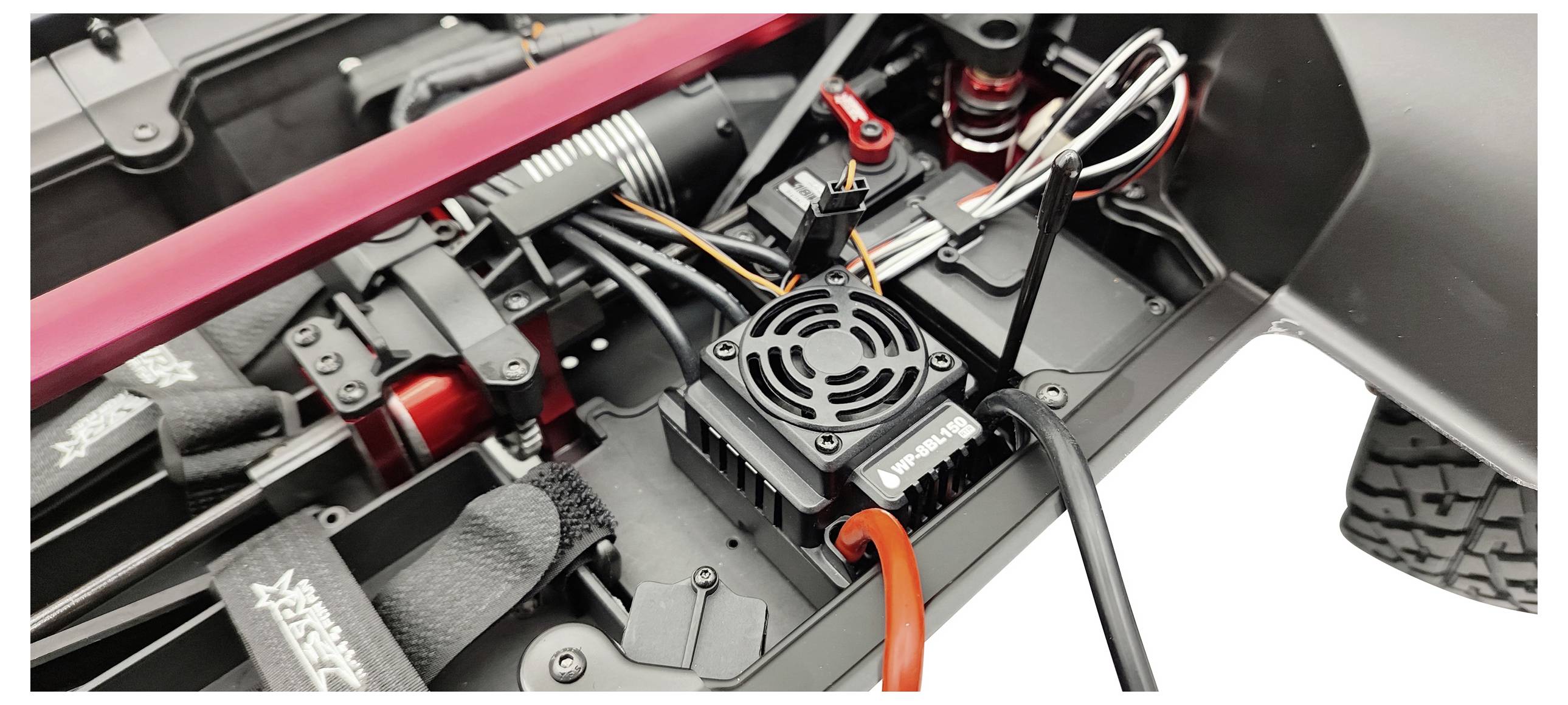 Nahaufnahme eines ferngesteuerten Autos zeigt Detail der Elektronik und Motorsteuerteile, Kabel und Verbindungen sind sichtbar.