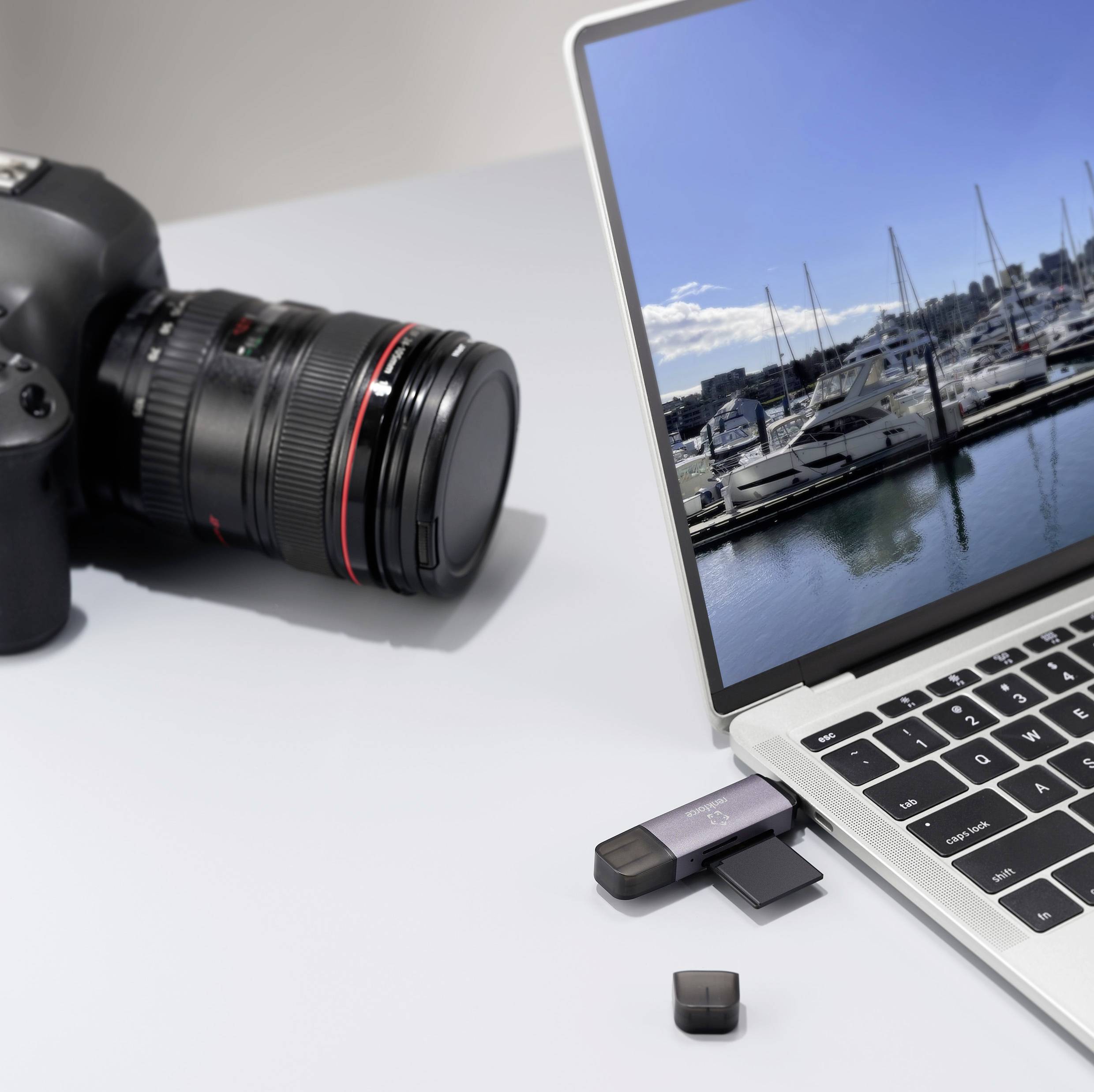 Laptop mit Foto von einem Yachthafen auf dem Bildschirm, daneben eine Kamera und USB-Sticks; Thema: Verbindung von Fotografie und Technik.