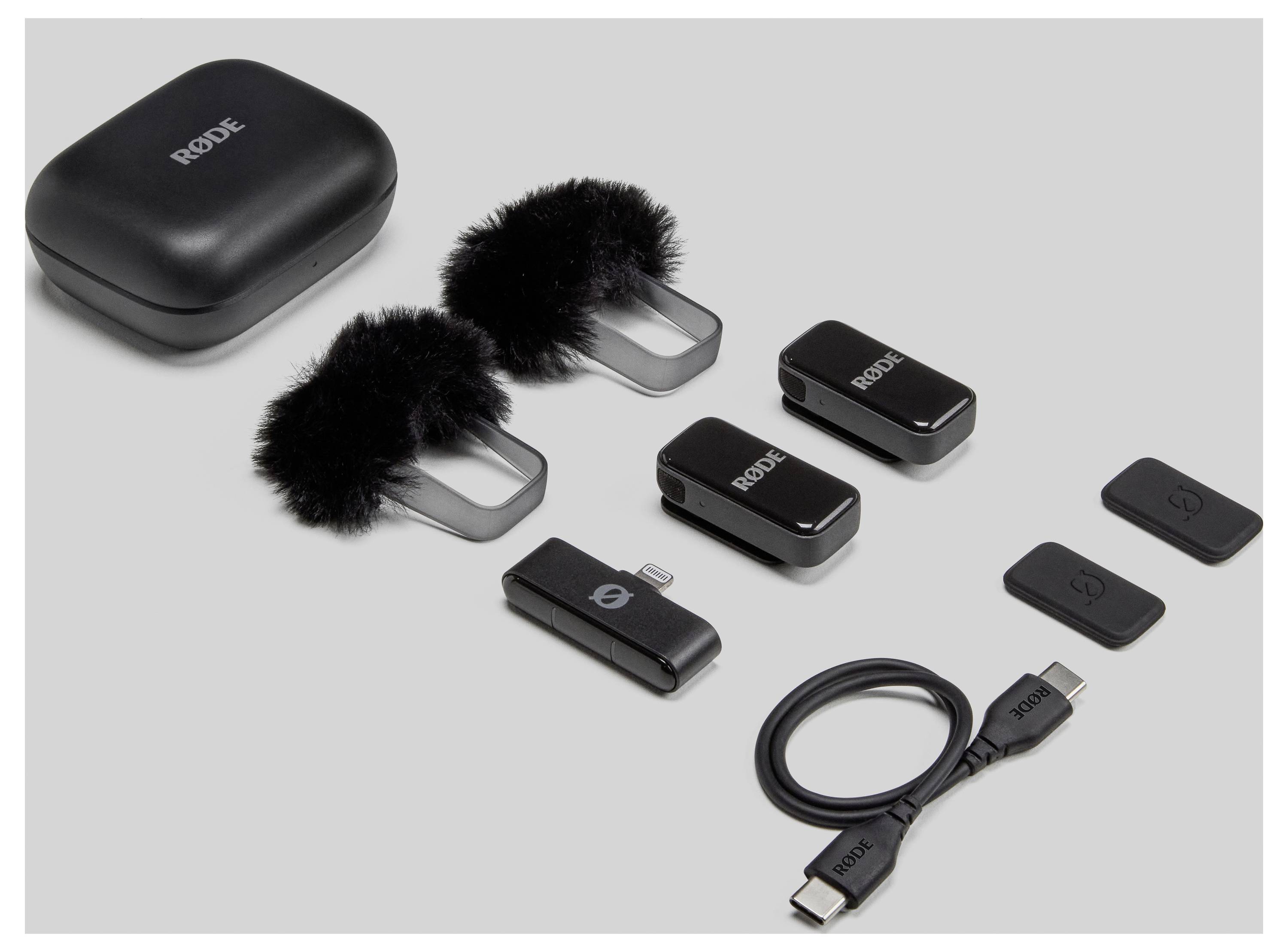 Kabelloses Mikrofon-Set bestehend aus Ladeetui, zwei Mikrofonen mit Windschutz, zwei Empfängern und USB-C-Kabel auf grauem Hintergrund.