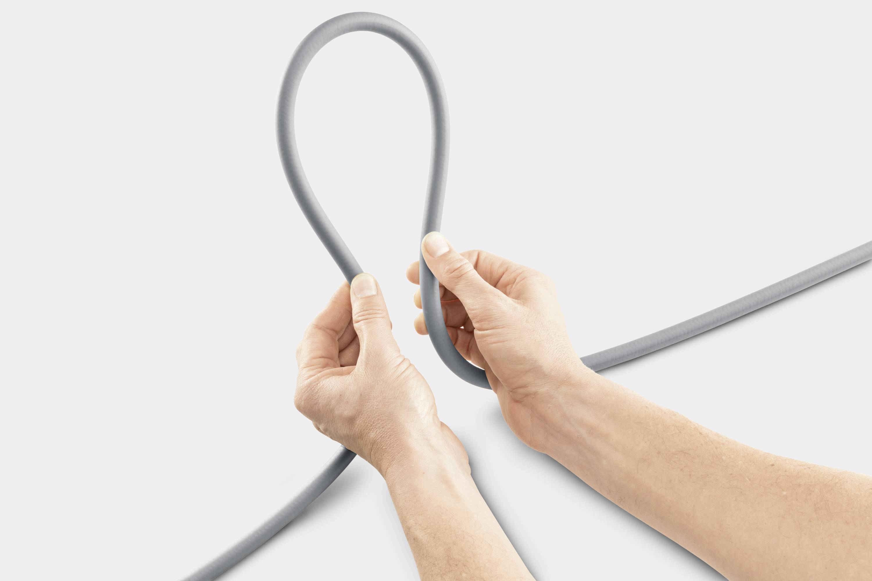 Ein Paar Hände formt aus einem grauen Kabel eine große Schlaufe. Der Hintergrund ist hellgrau.