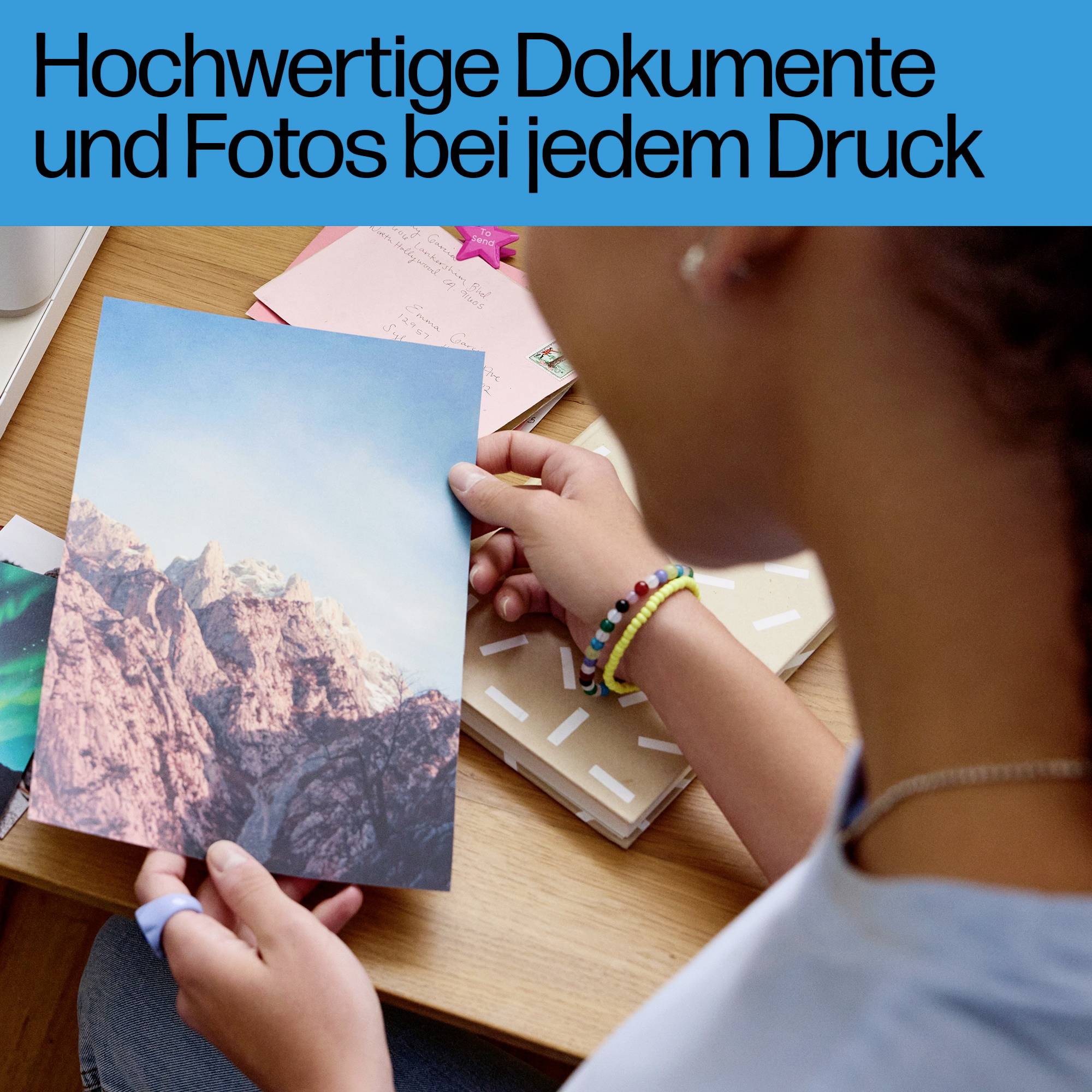 Eine Person hält ein Foto von Bergen. Text im Bild: 'Hochwertige Dokumente und Fotos bei jedem Druck'.