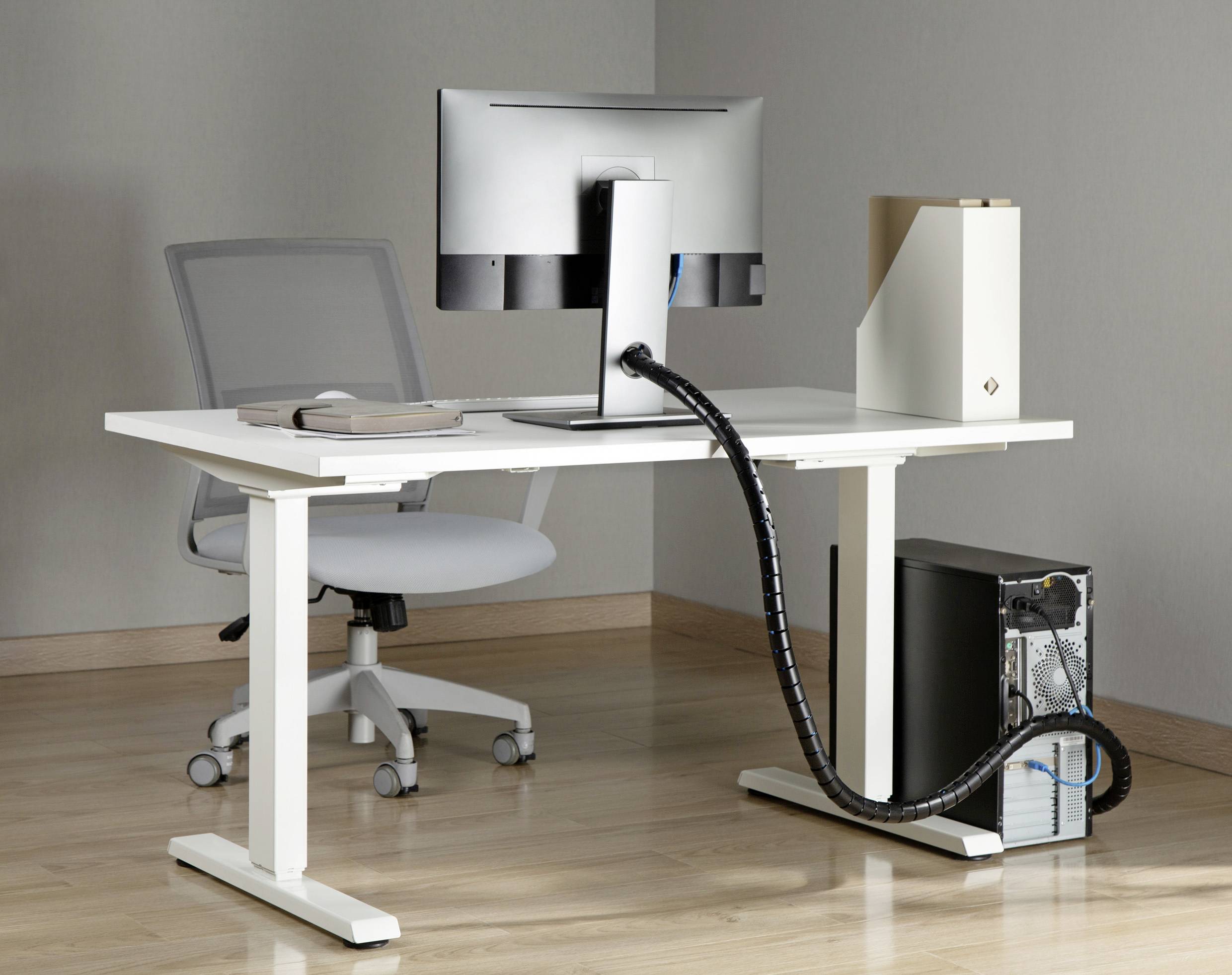 Ein moderner, ergonomischer Schreibtisch mit einem verstellbaren Bürostuhl. Auf dem Tisch stehen ein Monitor und ein Ordner.