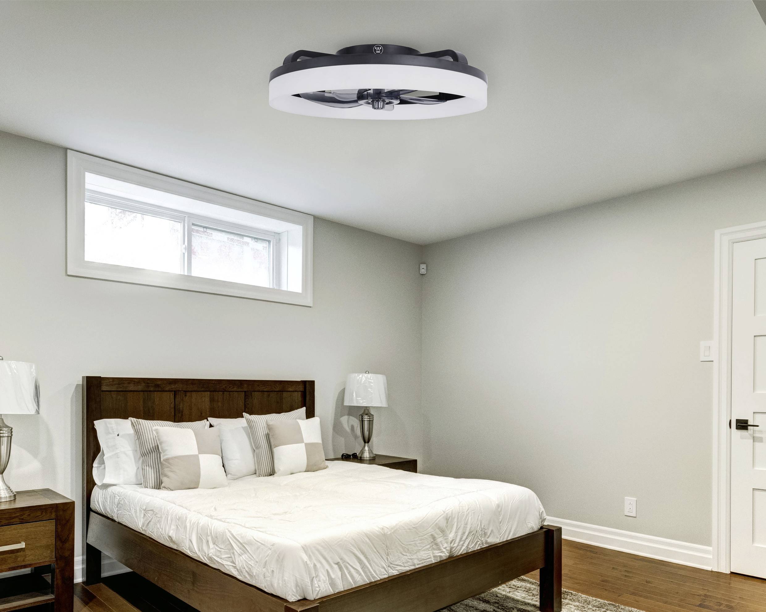 Helles Schlafzimmer mit modernem Deckenventilator und Doppelbett, umgeben von weißen Kissen und Holzmöbeln.