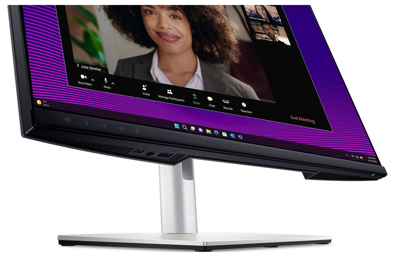 Ein Desktop-Monitor zeigt ein Videokonferenz-Tool mit einer Frau im Gespräch. Unten sind Symbole für Teilnehmerverwaltung und das Beenden des Meetings.