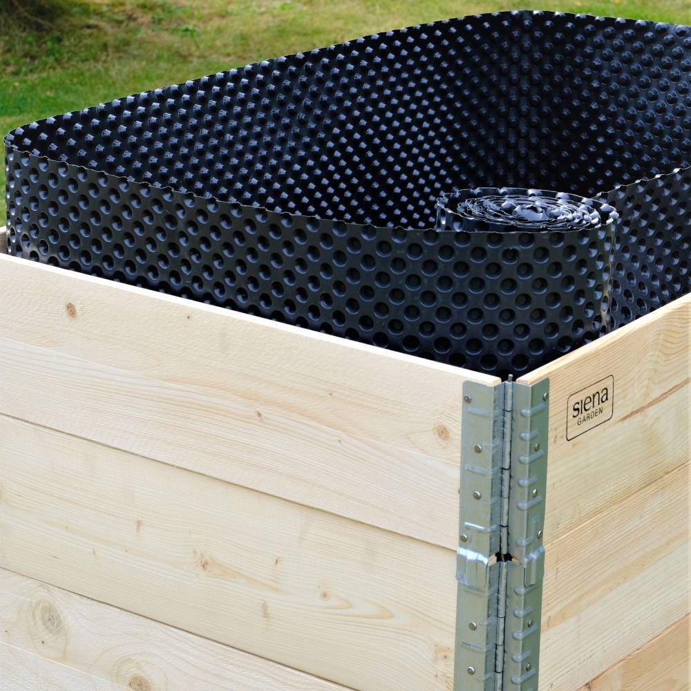 Eine Holzkiste enthält eine gerollte, schwarze Noppenfolie. Die Kiste steht im Freien auf einer Wiese.