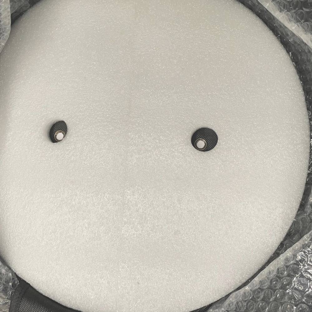 Eine runde, gepolsterte Struktur, umgeben von Luftpolsterfolie, mit zwei kleinen schwarzen Kreisen darauf, wohl zur Stabilisierung.