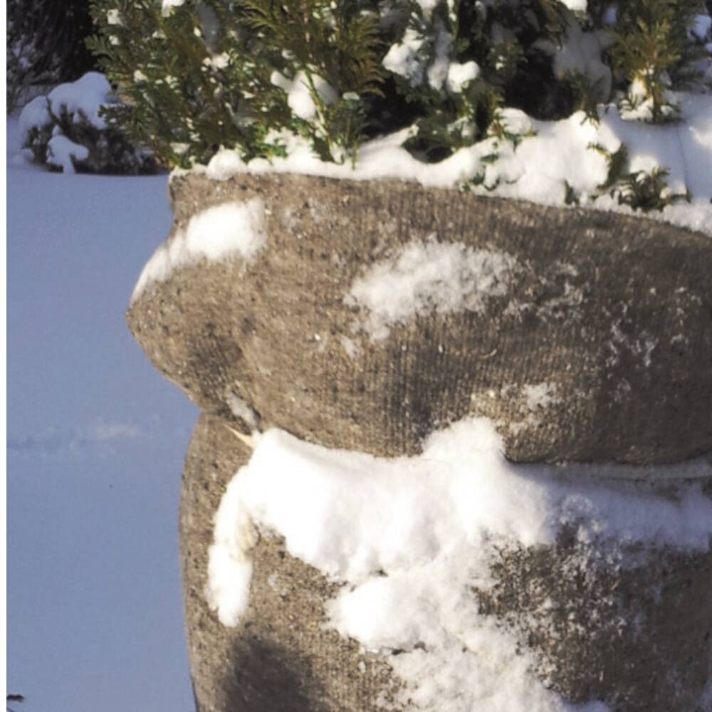 Ein mit Sackleinen umwickelter Baum steht im verschneiten Garten. Das Tuch schützt die Pflanze vor winterlichen Wetterbedingungen.