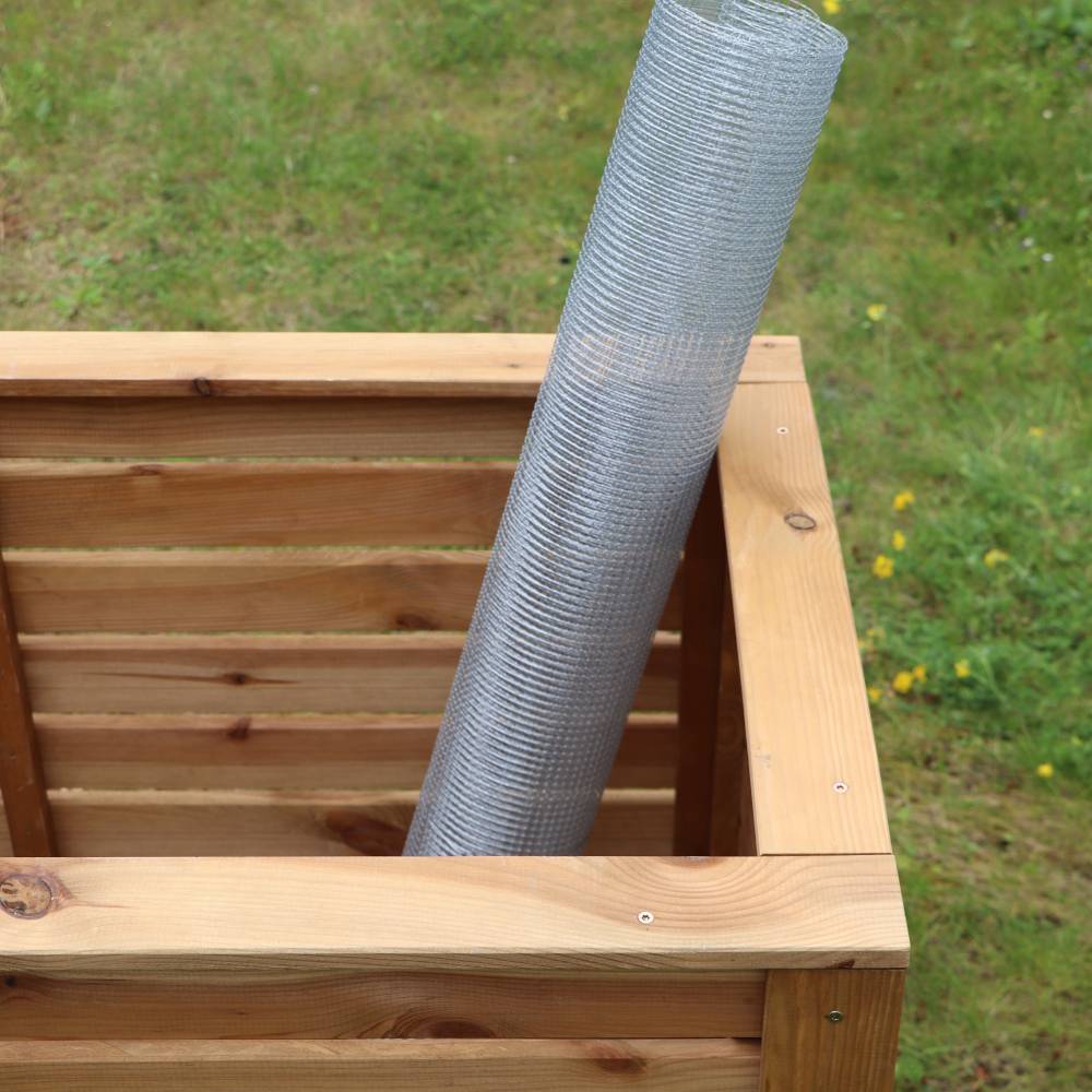 Holzkomposter im Garten mit eingesetztem Drahtgeflecht. Ideal zur Kompostierung von Gartenabfällen und Förderung nachhaltigen Gartenbaus.