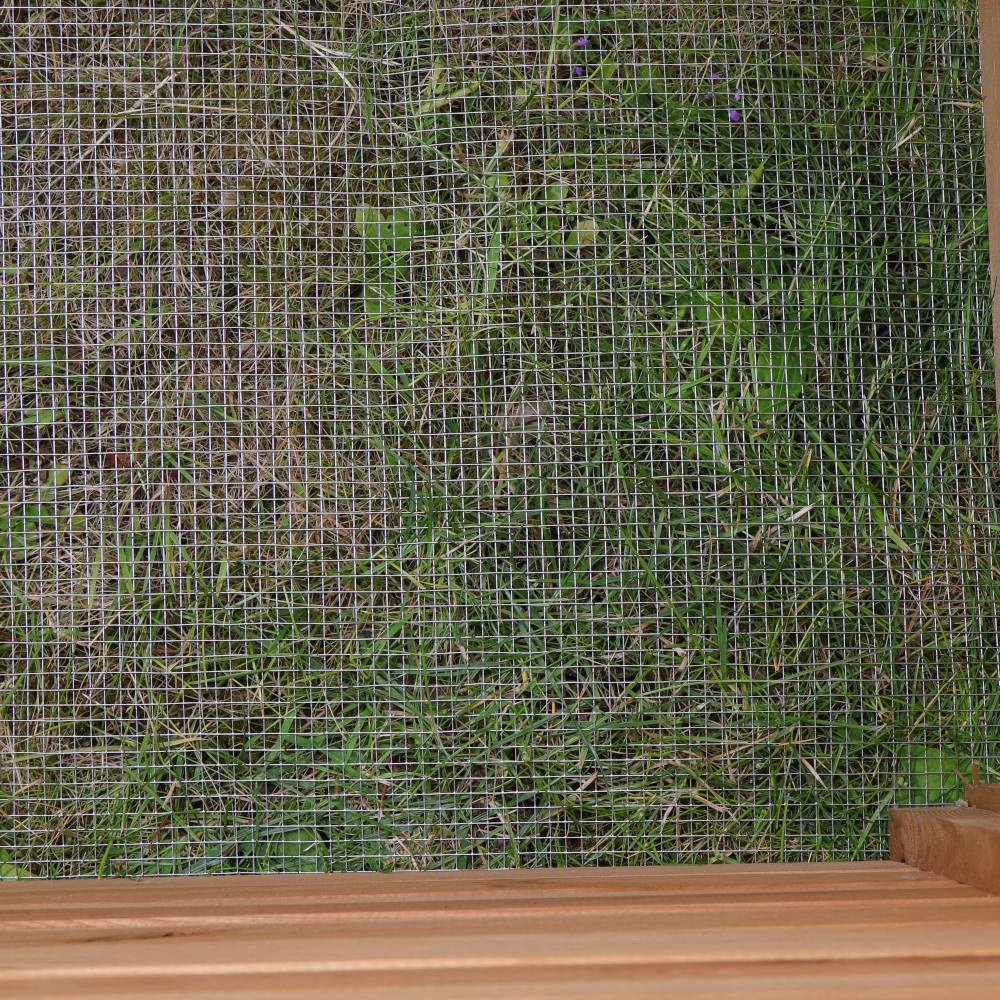 Holzregal vor einem Gitter, dahinter Gras.