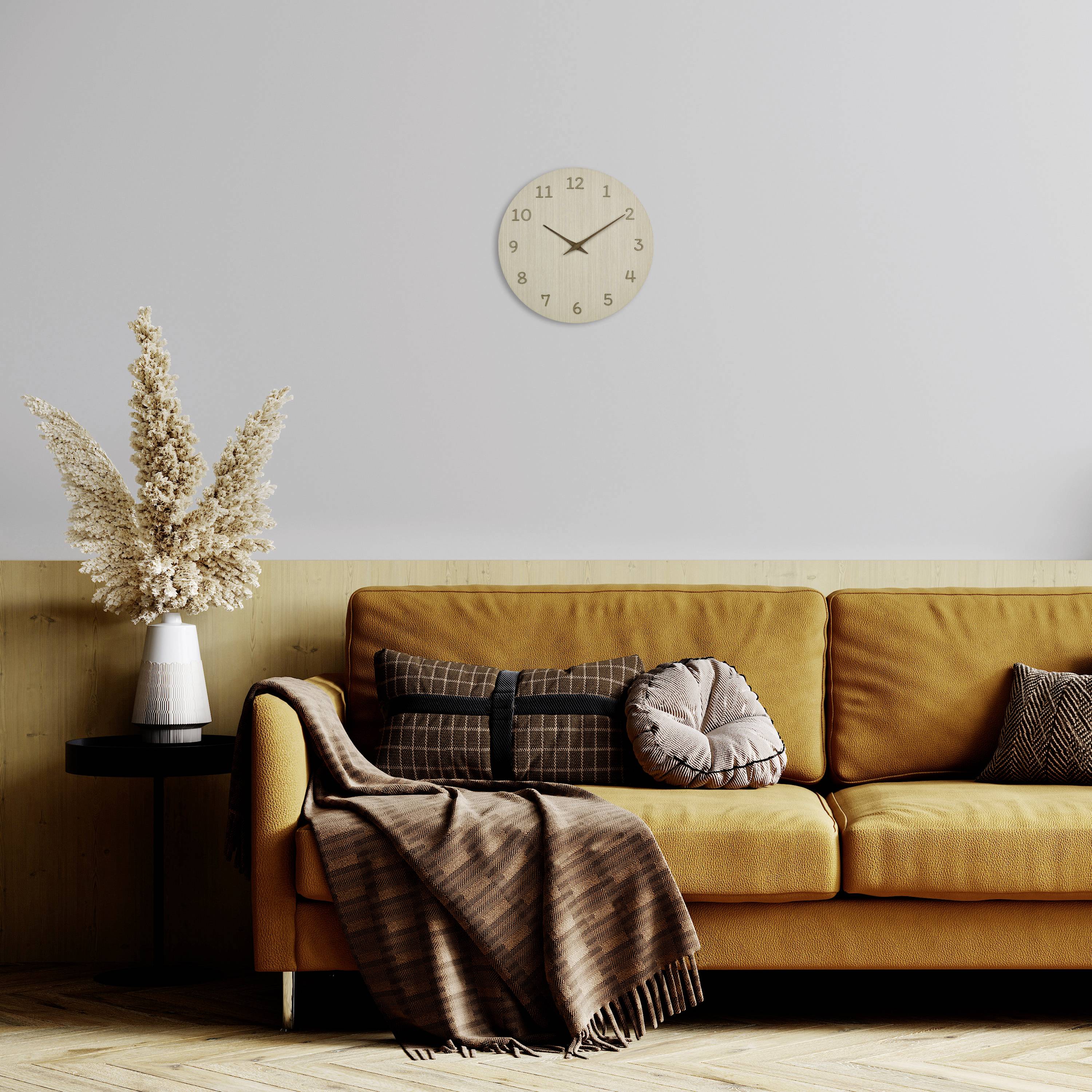 Ein Wohnzimmer mit einem gelben Sofa, dekorativen Kissen, einer Decke, einer Vase mit getrockneten Blumen und einer Wanduhr.