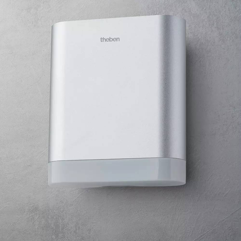 Eine rechteckige, silberne Außenbeleuchtung mit glatter Oberfläche an einer grauen Wand montiert. Markenname oben sichtbar.