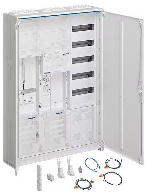 Ein großer, geöffneter Schaltschrank mit mehreren leeren Fächern und Füllstücken. Auf dem Boden befinden sich Kabel und Zubehörteile.