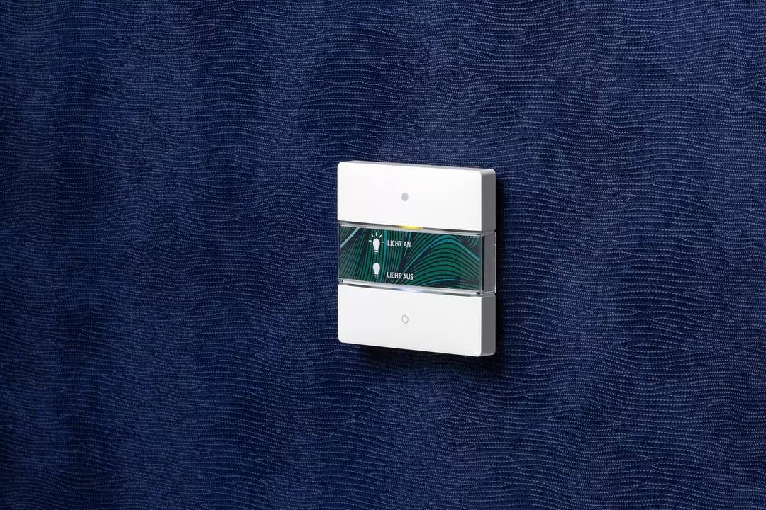 Ein Lichtschalter an einer blauen Wand. Der Schalter hat zwei Tasten mit den Beschriftungen 'Licht an' und 'Licht aus'.