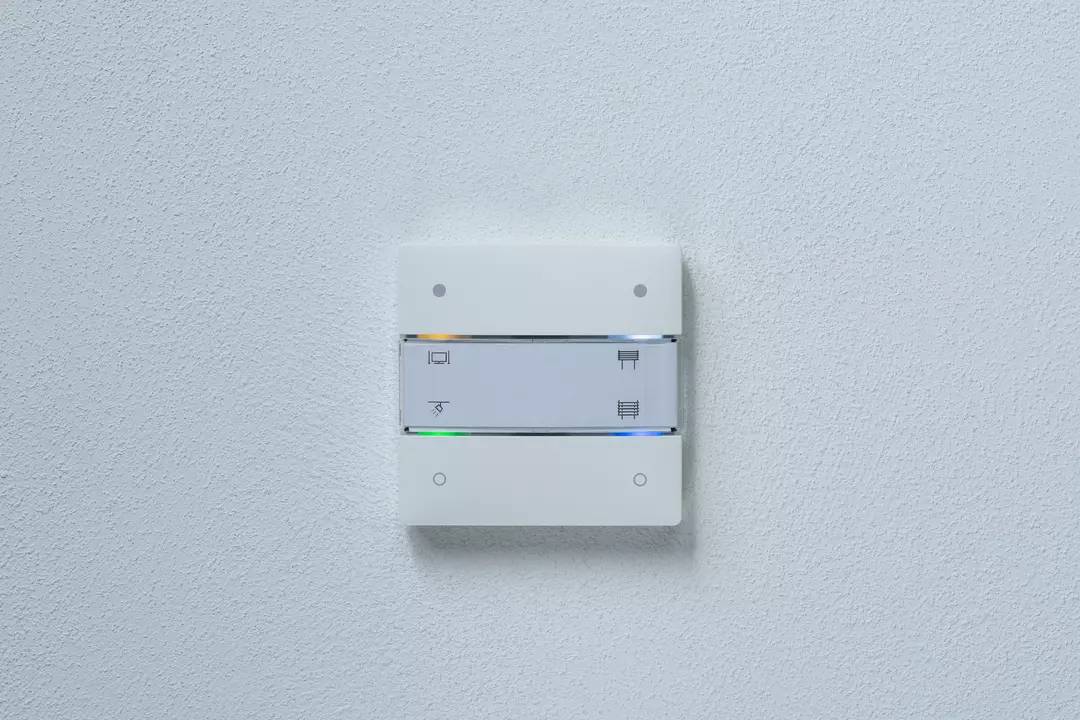 Weiße Lichtschalterplatte an der Wand mit zwei Kippschaltern und Symbolen.