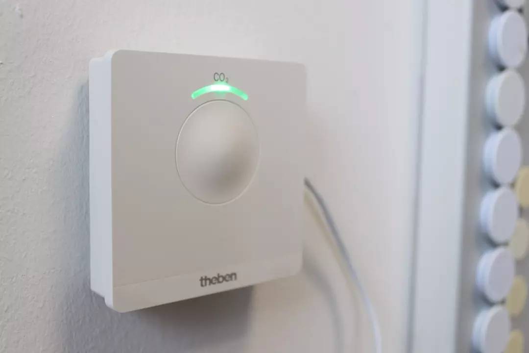 CO2-Sensor an der Wand, zeigt Luftqualität an. Das grüne Licht deutet auf normale CO2-Werte hin.