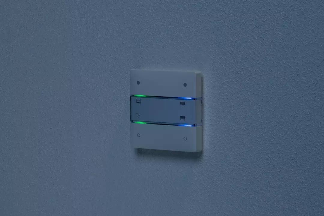 Ein beleuchteter Lichtschalter an einer Wand zeigt grüne und blaue Leuchtanzeigen.
