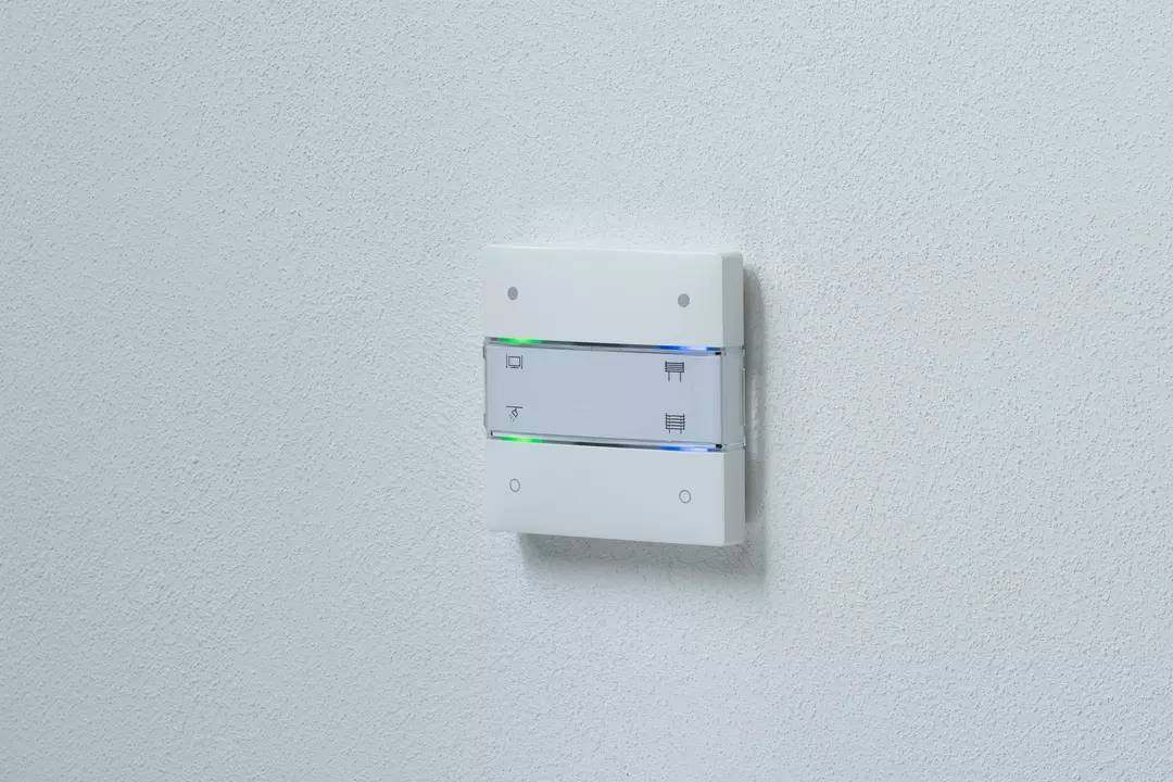 Ein weißer Lichtschalter mit Symbolen für Lichtsteuerung und Farben an der Wand.