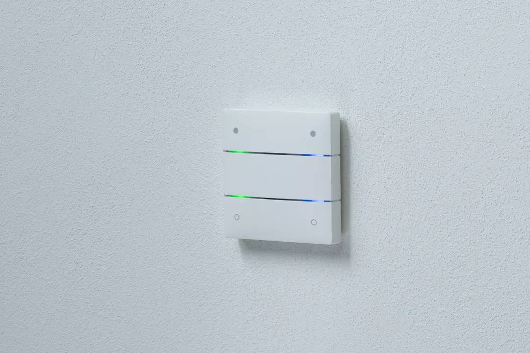 Ein elektronisches Wandgerät mit zwei leuchtenden LED-Streifen in Blau und Grün, montiert auf einer weißen Wand.