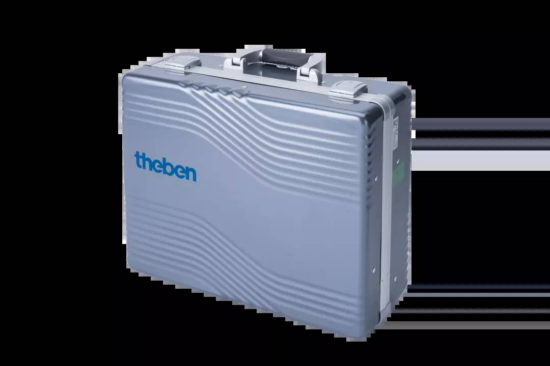 Silberner Metallkoffer mit 'theben' Logo, wellenförmige Linien auf der Oberfläche, Tragegriff oben, vor schwarzem Hintergrund.