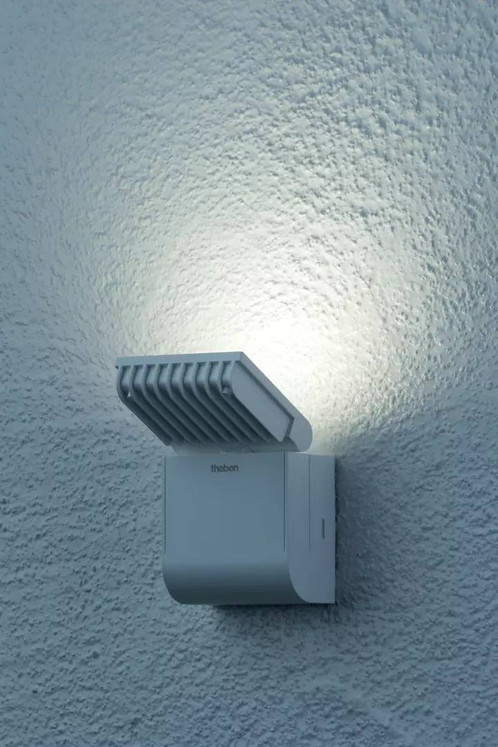 Ein moderner weißer Wandstrahler leuchtet gegen eine strukturierte Wand, erzeugt eine gleichmäßige Ausleuchtung und betont das Design.