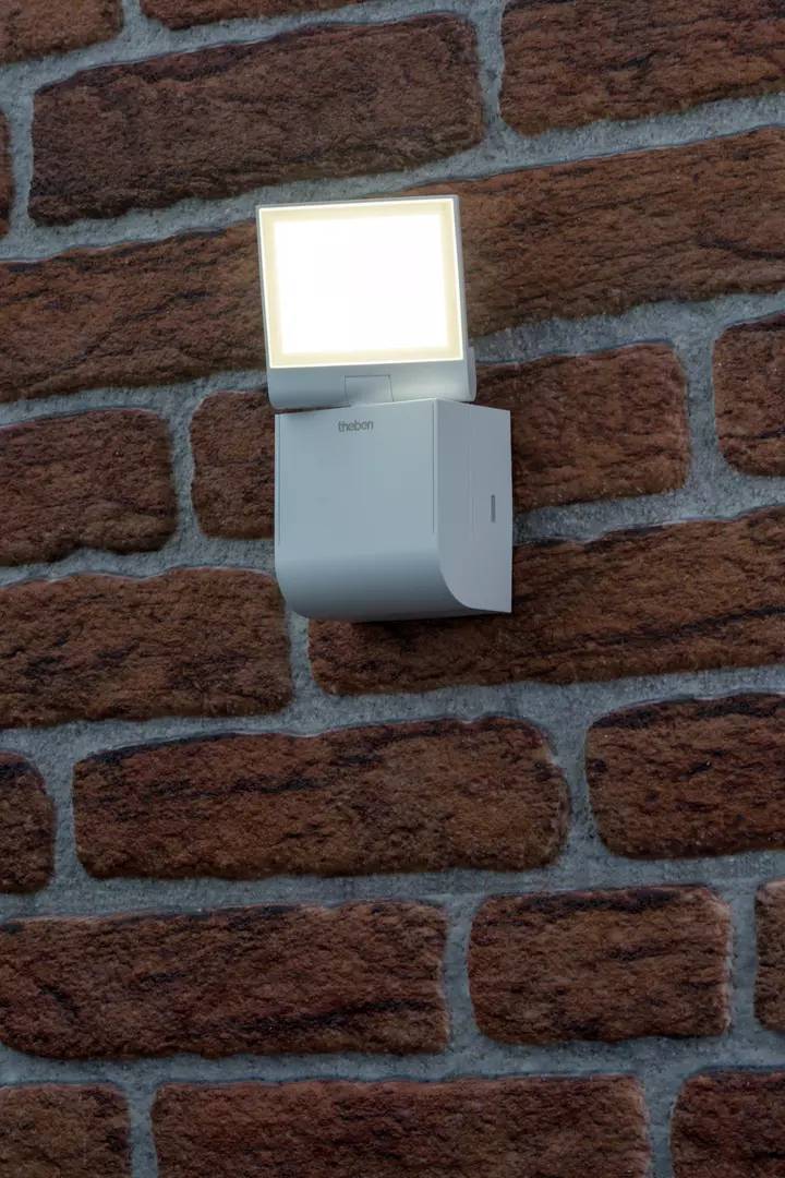 Außenleuchte mit rechteckigem, leuchtendem Kopf, montiert an einer Ziegelwand.