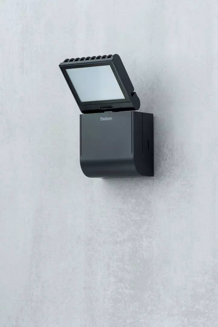 Eine schwarze Wandlampe mit integriertem Bewegungsmelder ist an einer grauen Betonwand montiert. Sie ist modern und funktional designt.