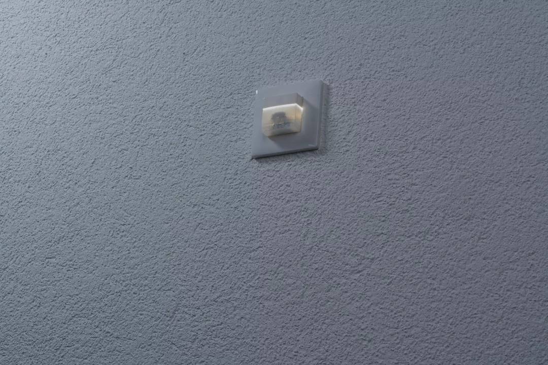 Ein Lichtschalter an einer blauen Wand, leicht beleuchtet.