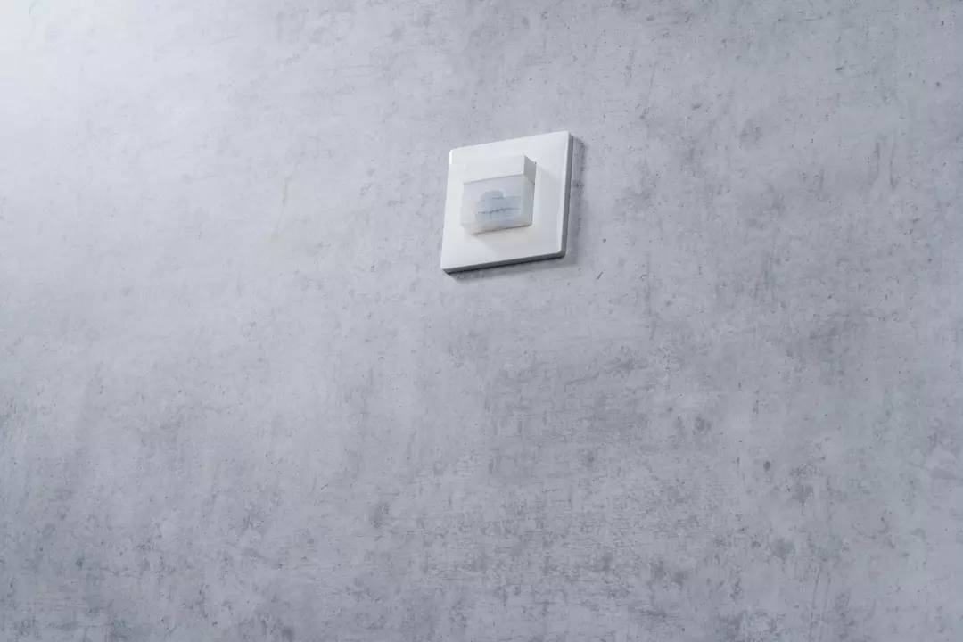 Ein einzelner Lichtschalter an einer grauen Wand.