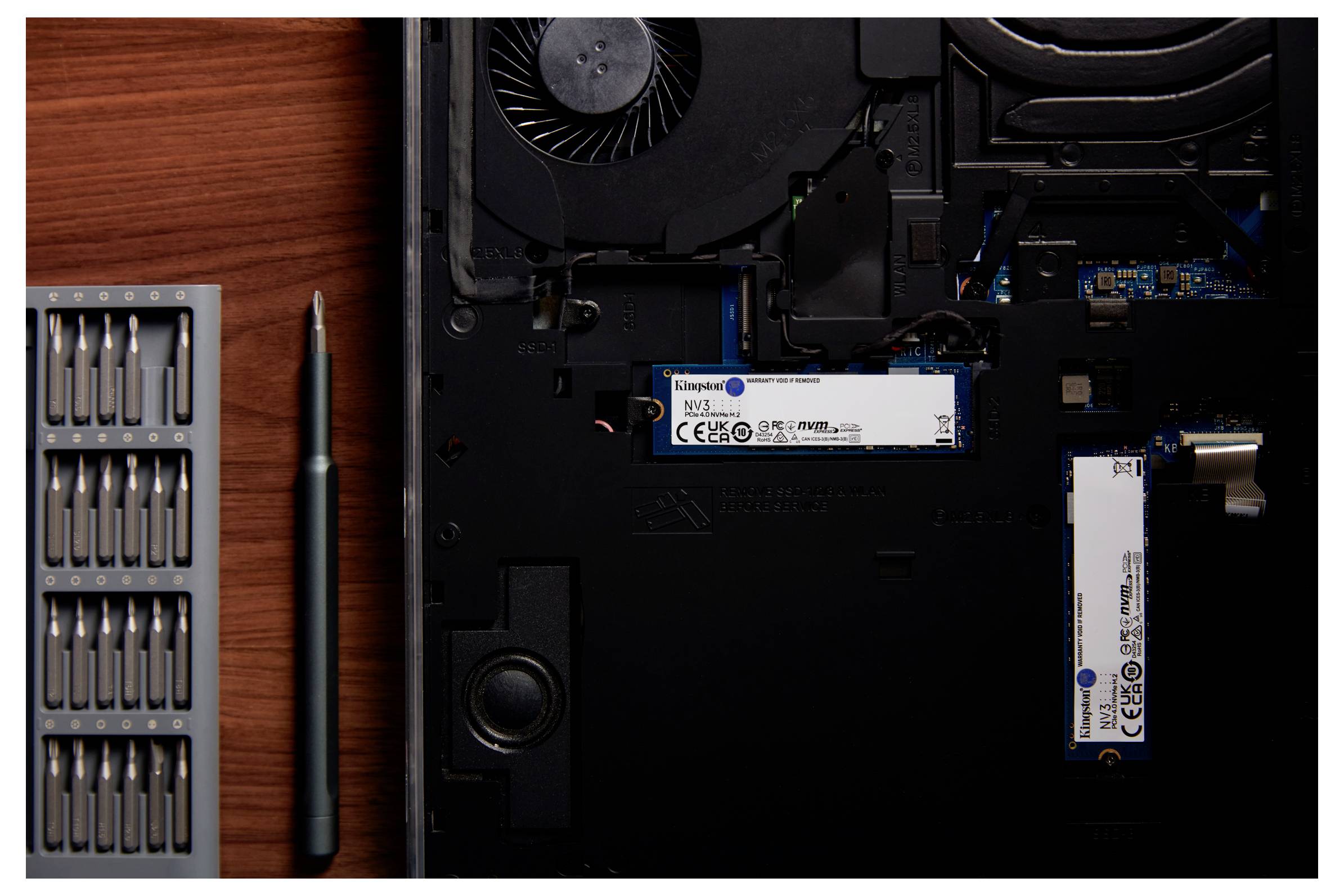 Offener Laptop mit sichtbaren internen Komponenten, einem installierten M.2 SSD-Laufwerk, einem Schraubendreher-Set und einem Schraubenzieher.