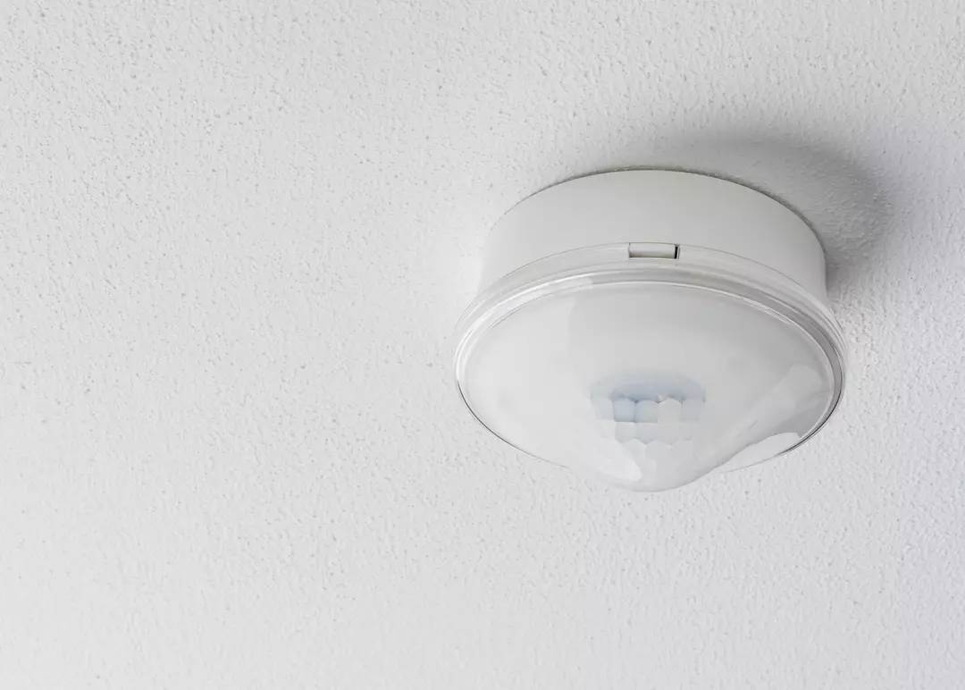 An der Decke montierter Rauchmelder mit weißem Gehäuse.