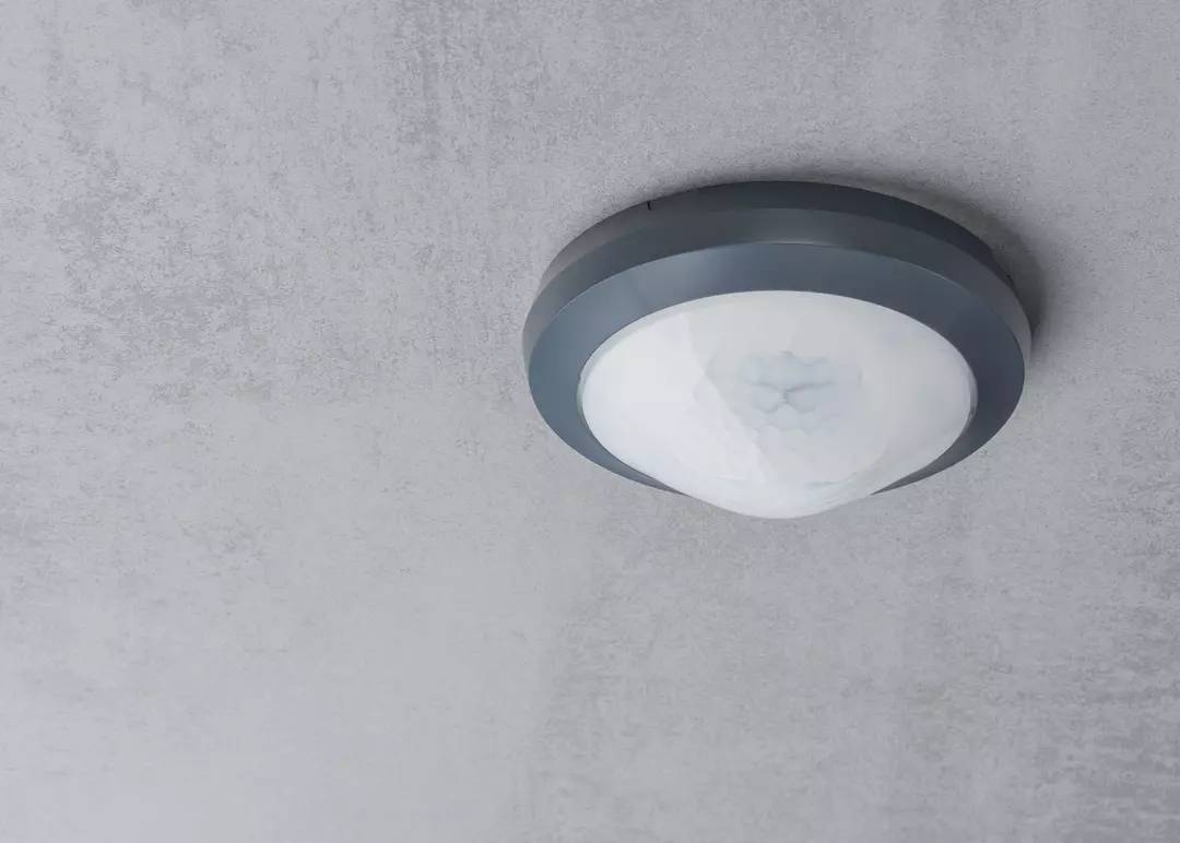 Deckenlampe mit rundem, modernem Design und weißem Diffusor. Befestigt an einer grauen Decke, Beleuchtung in klarer Optik.