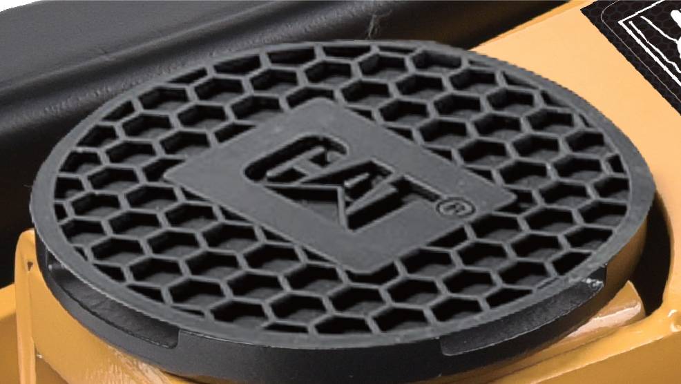 Nahaufnahme eines kreisförmigen Grills mit Wabenmuster, auf dem das 'CAT' Logo zu sehen ist, als Teil einer größeren Maschine.