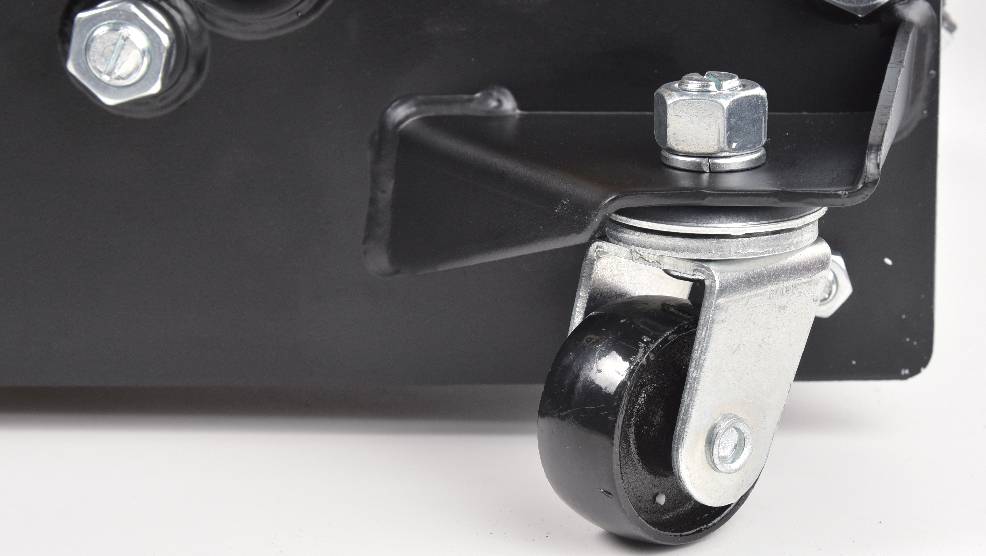 Eine Nahaufnahme eines Metallschwenkrads, das an der Ecke eines schwarzen Geräts befestigt ist und dabei das Rad und die Befestigungshalterung hervorhebt.