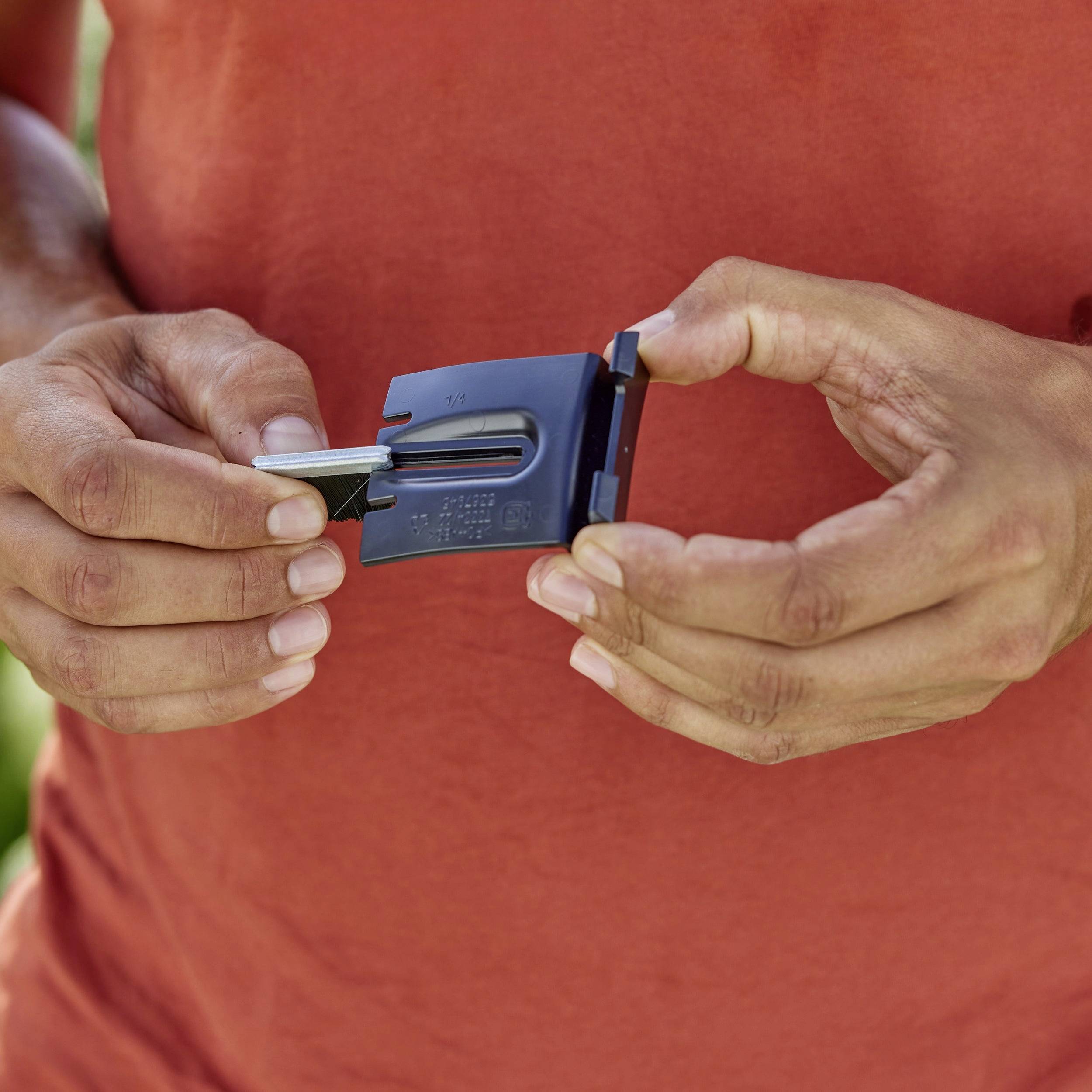 Person hält ein kleines, rechteckiges Gerät mit einem eingesetzten Schlüssel in beiden Händen. Hintergrund unscharf.