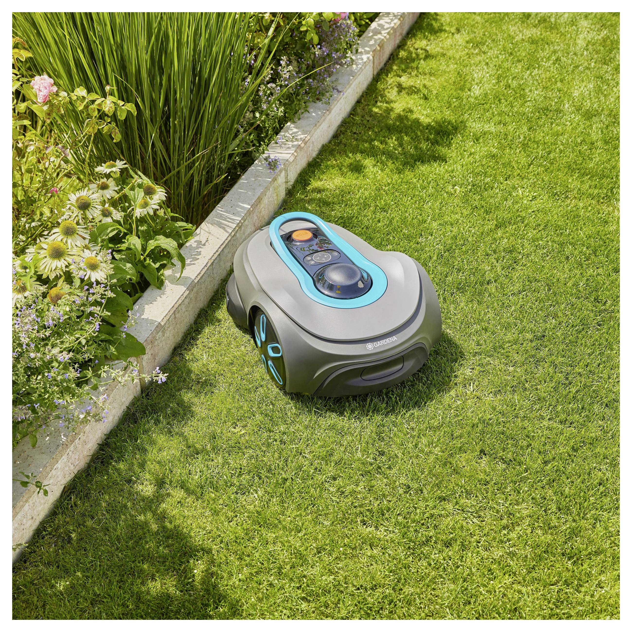 Ein Roboter-Rasenmäher auf grünem Rasen neben einem Blumenbeet, das den Rasen trimmt. Geeignet für automatisierte Gartenpflege.