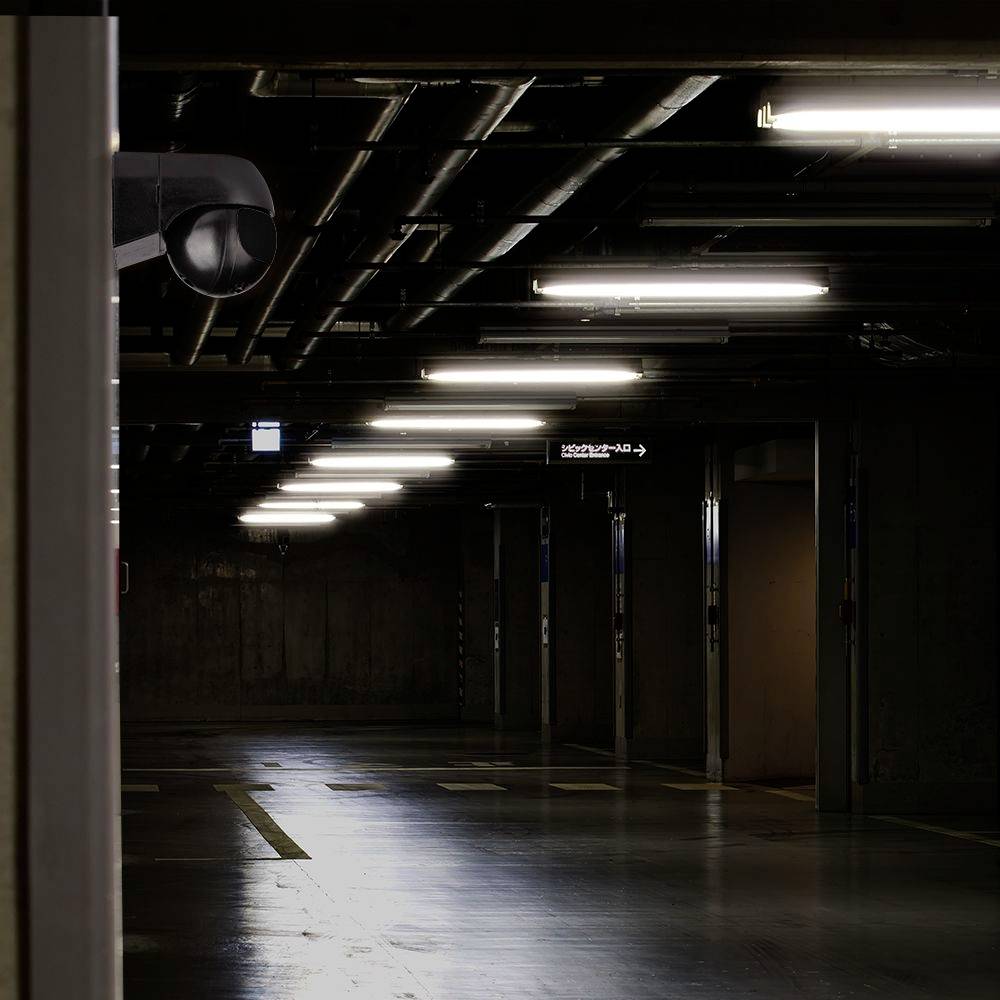 Eine leere, schwach beleuchtete Tiefgarage mit sichtbarer Überwachungskamera in der linken oberen Ecke.