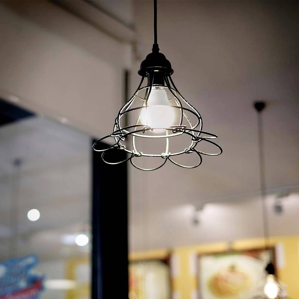 Eine stilvolle Hängelampe mit Metallrahmen hängt von der Decke in einem modern eingerichteten Raum mit verschwommenem Hintergrund.