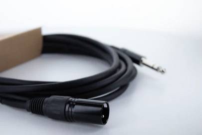 Ein Audio-Kabel mit XLR- und Klinkenstecker liegt auf einem weißen Untergrund. Es wird oft für Musik- und Audio-Anwendungen genutzt.
