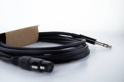 Schwarzes Audiokabel mit XLR- und Klinkenstecker liegt auf einem hellen Untergrund.