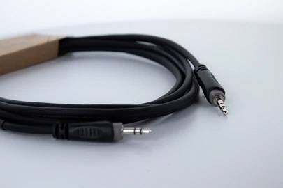 Ein schwarzes Audiokabel mit zwei 3,5-mm-Klinkensteckern auf einer weißen Oberfläche.