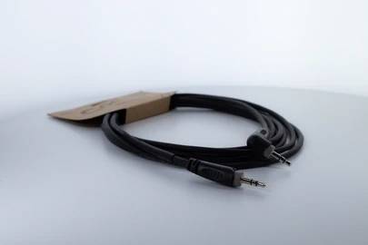 Schwarzes Audiokabel mit zwei 3,5-mm-Steckern, aufgerollt, auf einem weißen Hintergrund liegend.