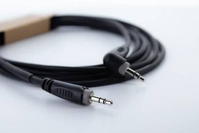 Schwarzes Audiokabel mit zwei Klinkensteckern auf weißem Hintergrund, das häufig zum Verbinden von Audiogeräten verwendet wird.