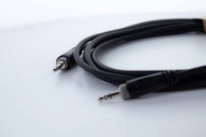 Ein schwarzes Audiokabel mit zwei 3,5-mm-Klinkensteckern liegt auf einem weißen Hintergrund.