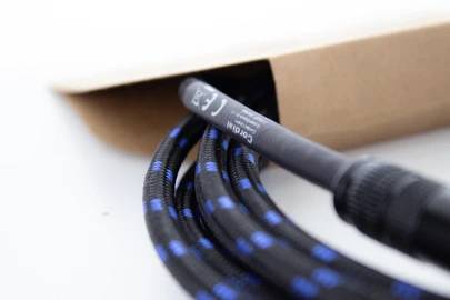 Ein schwarzes Kabel mit blauen Punkten ragt aus einer braunen Verpackung. Auf dem Kabel steht 'Cat 6 LAN', ein Netzwerk-Kabel.