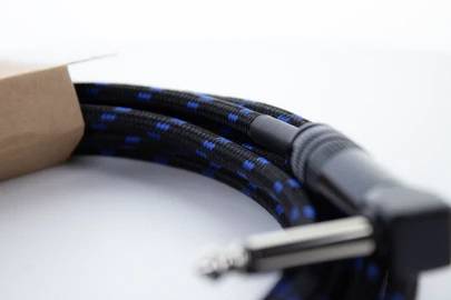 Schwarzes Audiokabel mit blauen Markierungen und einem Metallstecker auf weißem Hintergrund, teilweise in Kartonverpackung.