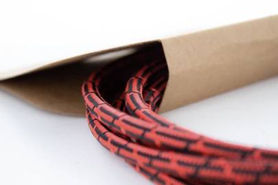 Ein rot-schwarz gemustertes Kabel ragt aus einem braunen Papierumschlag.