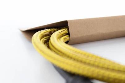 Gelbes Kabel, teilweise aus einer braunen Papierverpackung herausgezogen, auf einem weißen Hintergrund.
