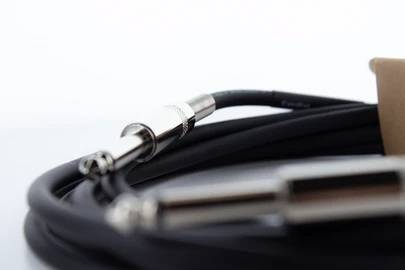 Ein schwarzes Audiokabel mit silbernen Klinkensteckern liegt auf einer weißen Oberfläche.