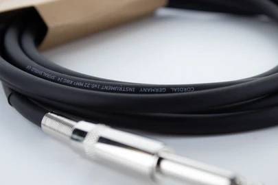 Ein schwarzes Audiokabel mit silbernem Stecker auf weißem Hintergrund. Aufschrift auf dem Kabel: 'GERMANY INSTRUMENT CORDIAL'.